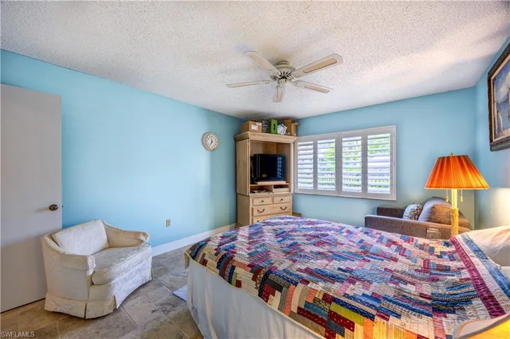 Bedroom with a textured ceiling, ceiling fan, stone finish floor, and baseboards