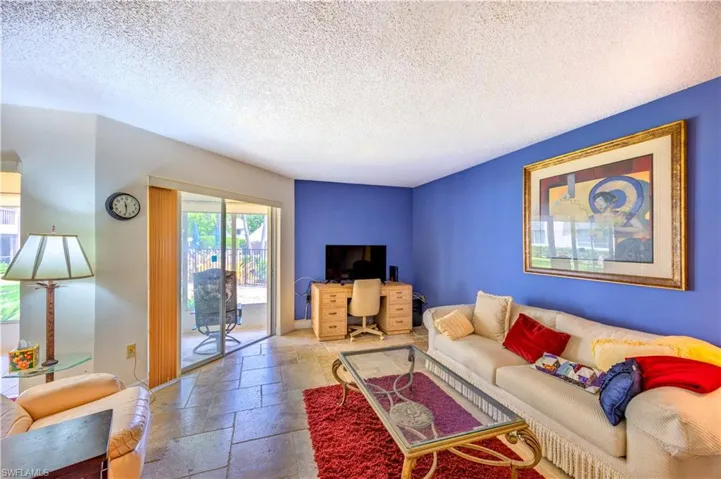 Living area with a textured ceiling, stone tile floors, and baseboards