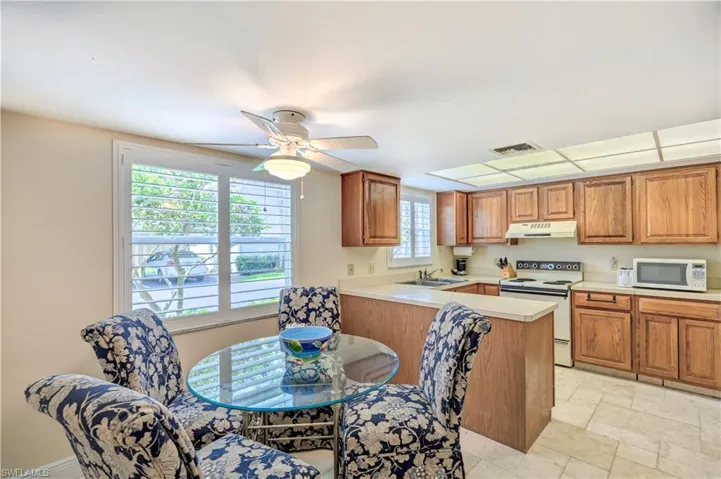 Kitchen featuring white appliances, under cabinet range hood, light countertops, visible vents, and a peninsula