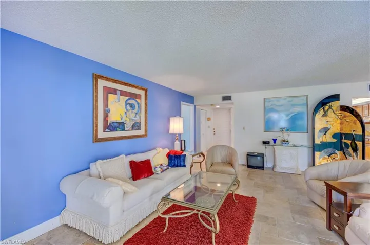 Living room featuring baseboards, visible vents, a textured ceiling, and stone finish floor