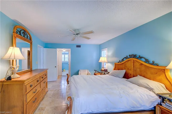 Bedroom with a textured ceiling, visible vents, a ceiling fan, and stone tile flooring