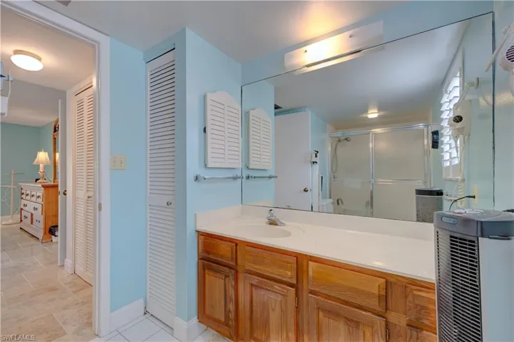 Full bath featuring a stall shower, a closet, vanity, and baseboards