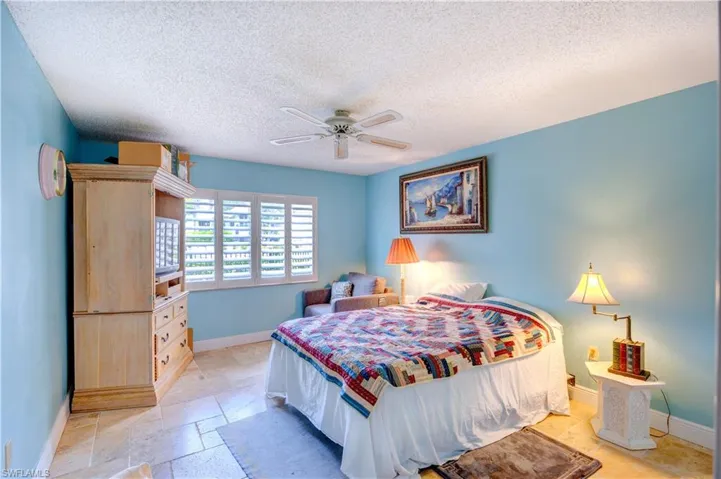 Bedroom with a textured ceiling, ceiling fan, and baseboards