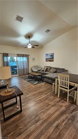 Vaulted ceiling, wood-finish flooring, ceiling fan with integrated lighting, sliding glass door, and recessed lighting