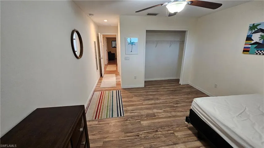 Spacious interior featuring wood-finish flooring, a ceiling fan with integrated lighting, and an open closet space