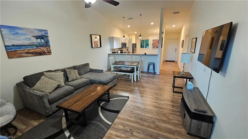 High ceilings with recessed lighting, wood-finish flooring, a kitchen island with pendant lighting, and an integrated dining area