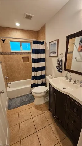Bathroom featuring a built-in tub with tile surround and mosaic accent, a vanity with an integrated sink, a wall-mounted mirror, and tile flooring