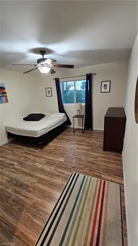 Ceiling fan with integrated lighting, wood-finish flooring, white walls, and a window