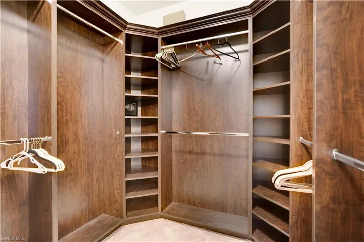 Walk in closet with builkt-in shelving and wall safe