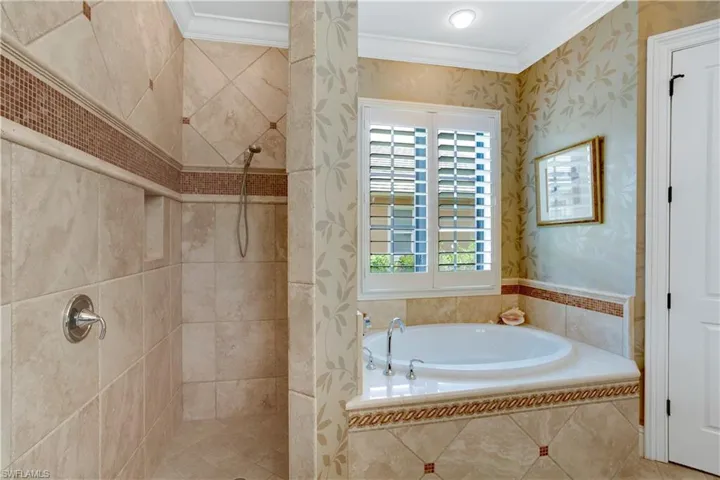 Full bathroom with ornamental molding, a bath, tiled shower, and wallpapered walls