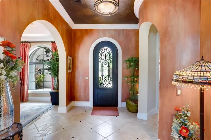 Entryway with Custom Wrought Iron Door, faux painted walls and ceiling, ornamental molding and stone travertine floor