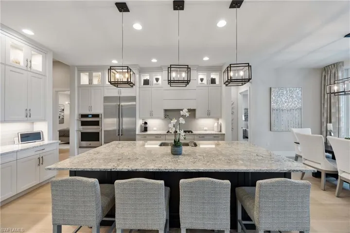 Kitchen with backsplash, recessed lighting, appliances with stainless steel finishes, light stone countertops, and light wood finished floors