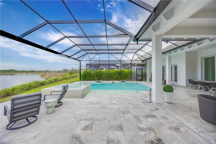 View of pool with a patio, a sunroom, glass enclosure, a pool with connected hot tub, and a water view