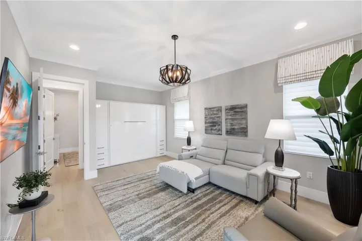 Living area featuring light wood-type flooring, a chandelier, recessed lighting, and ornamental molding