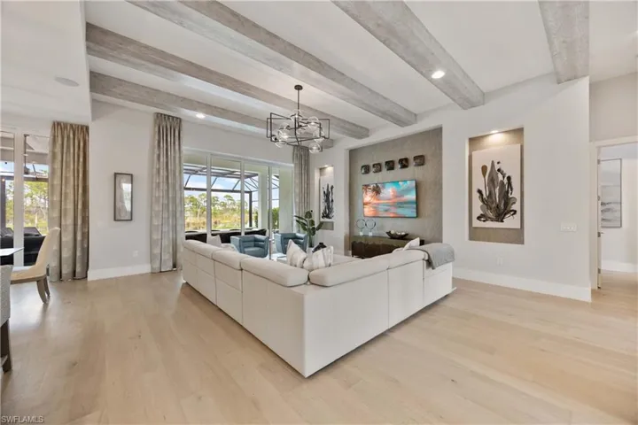Living area with beam ceiling, light wood-style floors, recessed lighting, and a chandelier