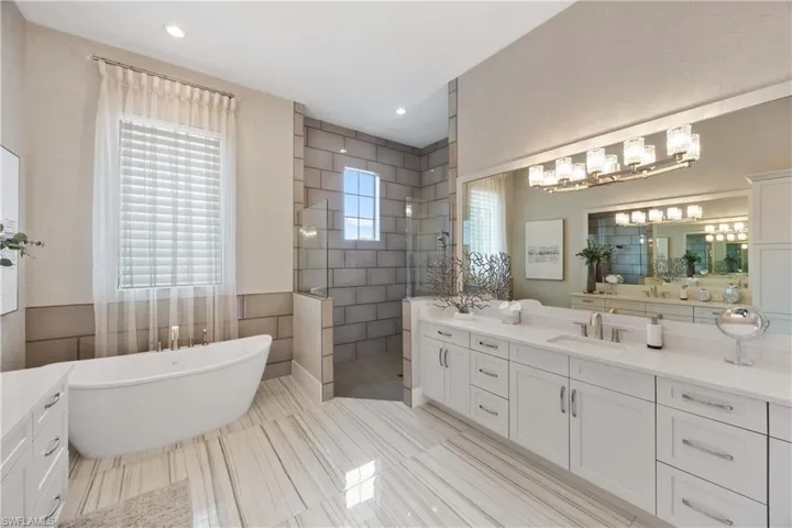 Full bath featuring a freestanding bath, walk in shower, vanity, tile walls, and recessed lighting