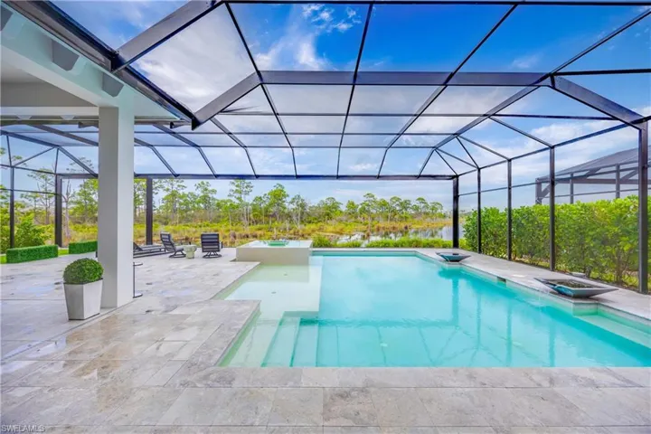 View of pool featuring a sunroom, a lanai, a pool with connected hot tub, and a patio