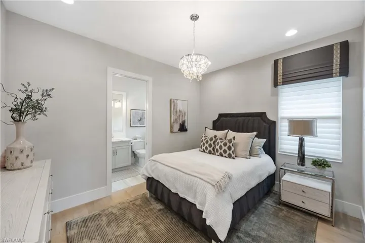 Bedroom with light wood finished floors, a chandelier, recessed lighting, and connected bathroom