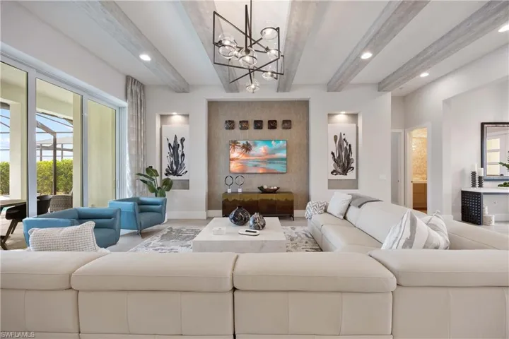 Living room with beamed ceiling, healthy amount of natural light, a chandelier, and recessed lighting