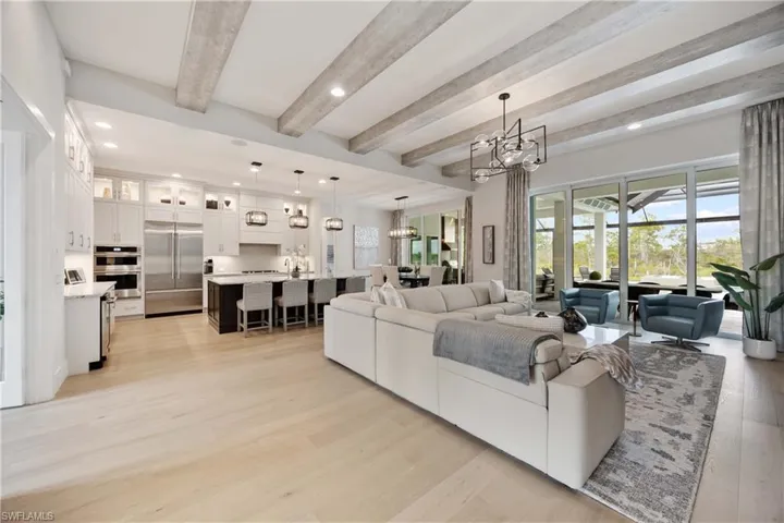 Living room featuring beam ceiling, a chandelier, light wood-style floors, and recessed lighting