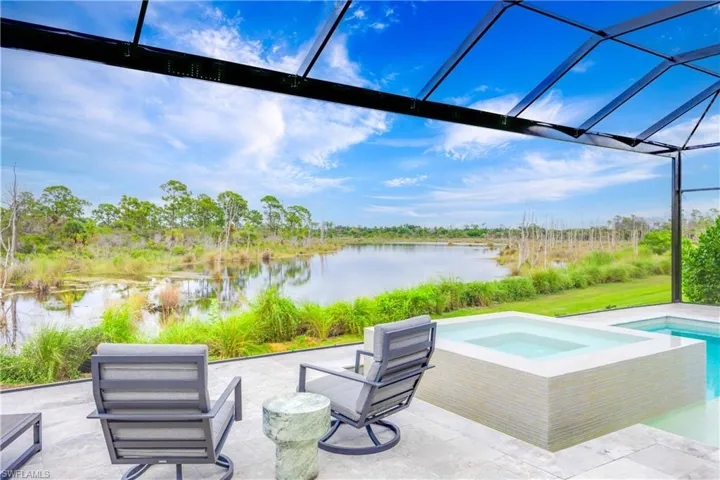 View of patio / terrace with a water view, a lanai, a pool with connected hot tub, and a sunroom