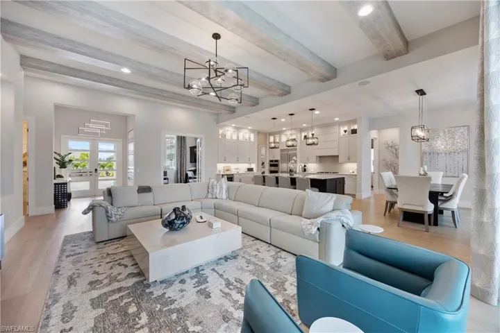 Living room featuring a chandelier, recessed lighting, beam ceiling, and light wood-style flooring