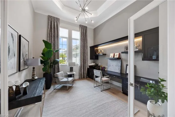 Office area featuring a tray ceiling, light wood-style flooring, and ornamental molding