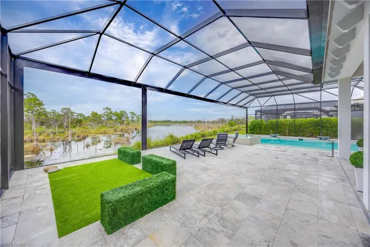 View of patio featuring a sunroom, a lanai, a water view, and an outdoor pool