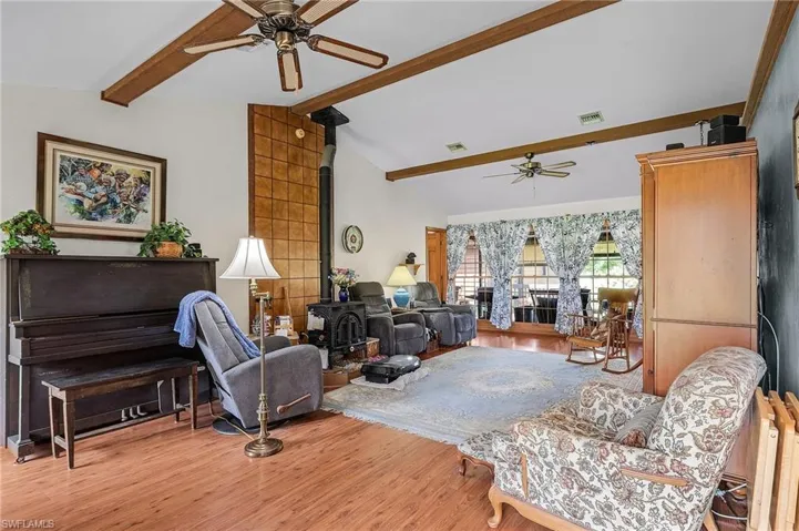 Living room with a ceiling fan, wood finished floors, and a wood stove