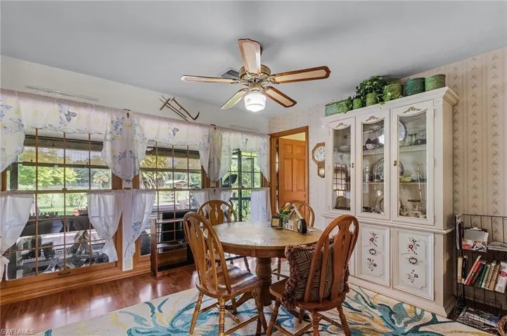 Dining space with wallpapered walls, wood finished floors, and a ceiling fan
