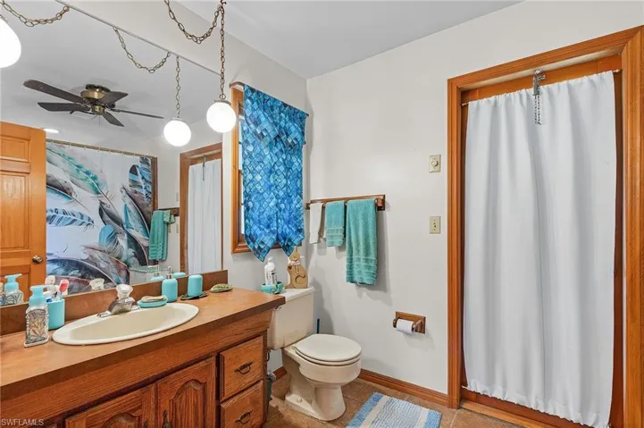 Full bath featuring vanity, tile patterned flooring, ceiling fan, and curtained shower