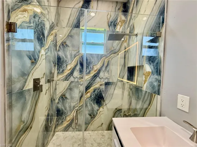 Bathroom with a marble finish shower and vanity