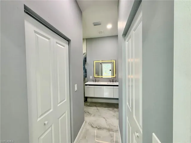 Hall featuring light marble finish floors and a sink