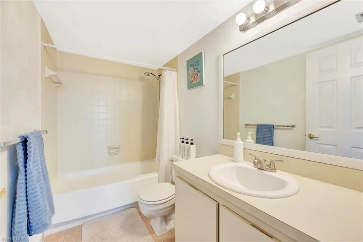 Bathroom featuring shower / bath combo with shower curtain, vanity, and light tile patterned flooring