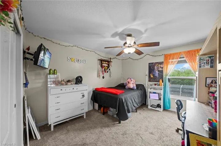 Bedroom with light carpet, ceiling fan, and a textured ceiling