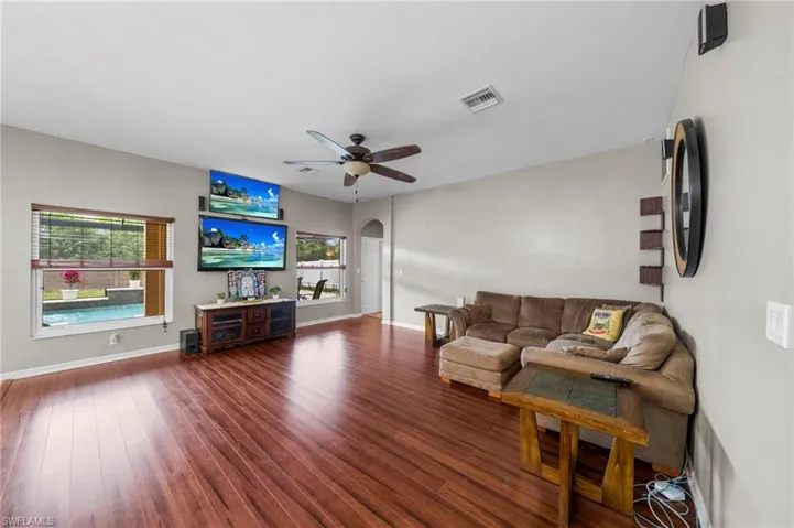 Living room featuring arched walkways, dark wood-type flooring, and ceiling fan
