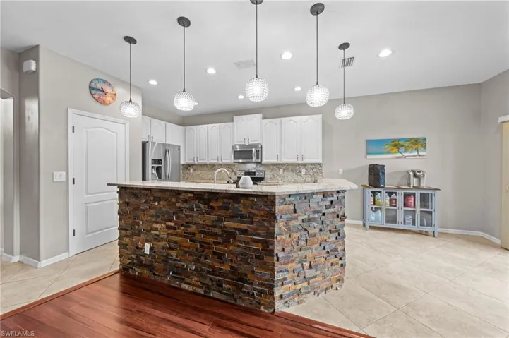 Kitchen with white cabinets, hanging light fixtures, stainless steel appliances, light tile patterned flooring, and recessed lighting
