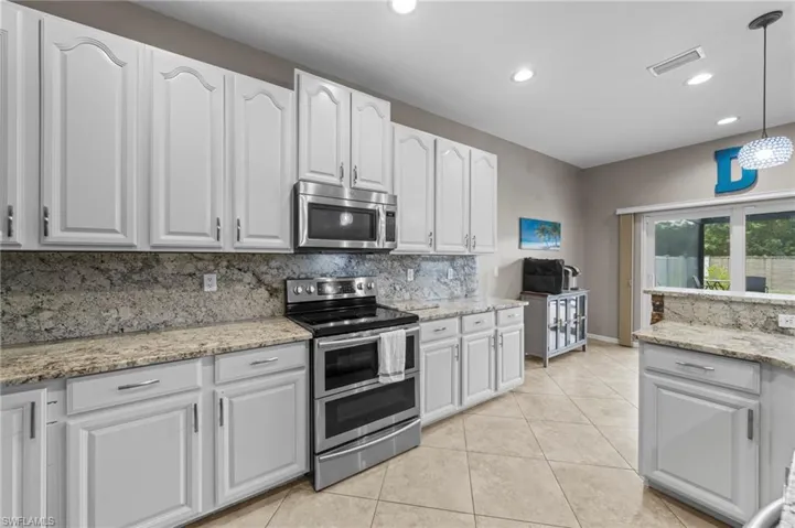 Kitchen featuring appliances with stainless steel finishes, white cabinetry, light stone counters, recessed lighting, and light tile patterned floors