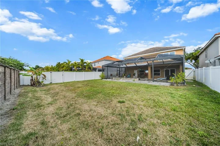 Back of property featuring a fenced backyard, a lanai, a sunroom, and a patio