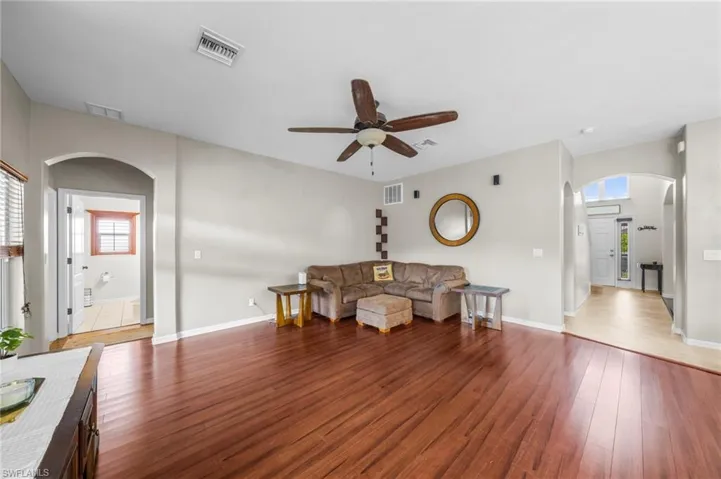 Living area with arched walkways, ceiling fan, and wood-type flooring