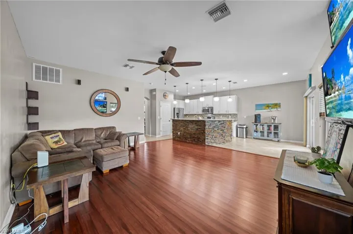 Living room featuring dark wood finished floors, ceiling fan, and recessed lighting