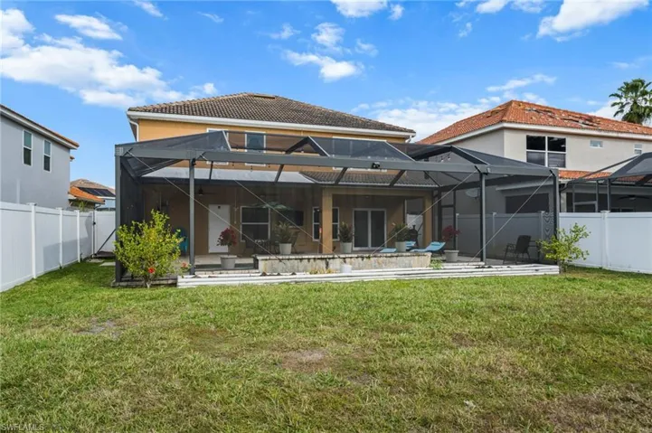 Back of property with a fenced backyard, a lanai, and a patio area