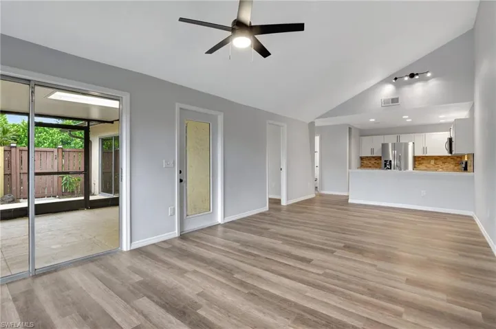 Unfurnished living room with LVT floor, high vaulted ceiling, and ceiling fan