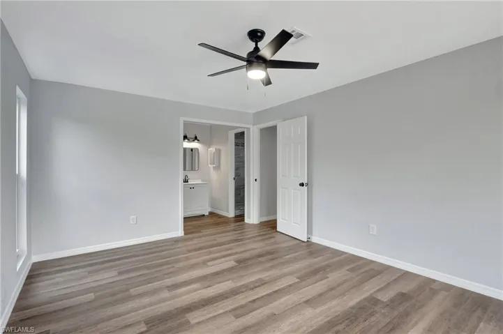 Primary bedroom with connected bathroom, ceiling fan, and light LVT flooring