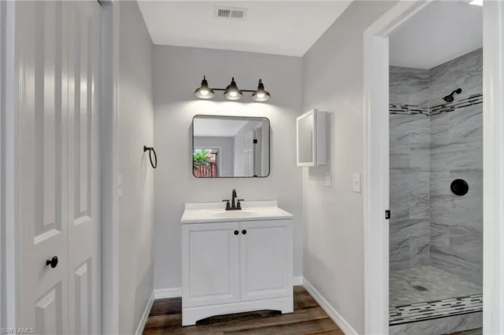Bathroom with vanity, LVT flooring, and tiled shower