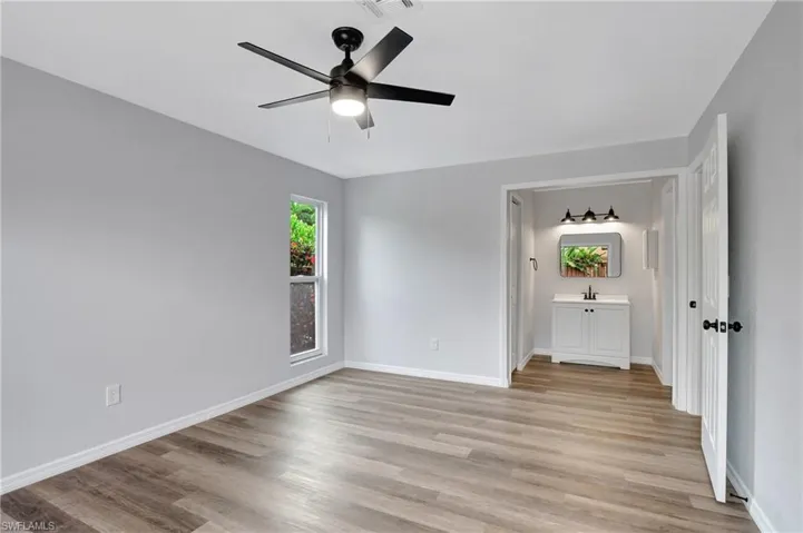 Primary bedroom featuring LVT flooring, ensuite bathroom, and ceiling fan