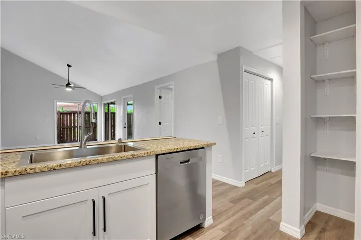 Kitchen with sink, dishwasher, LVT flooring, white cabinetry