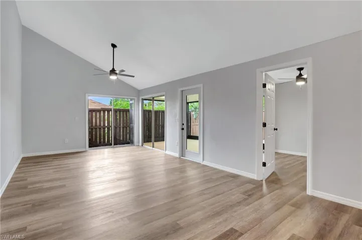 Unfurnished room with LVT floor, vaulted ceiling, and ceiling fan