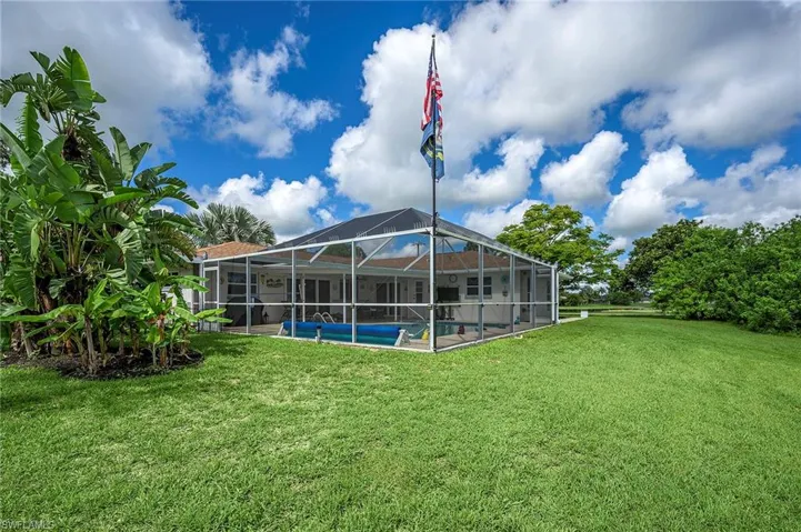 Back of property with a lanai and a lawn
