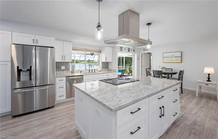 Kitchen with light hardwood / wood-style floors, stainless steel appliances, island exhaust hood, hanging light fixtures, and tasteful backsplash